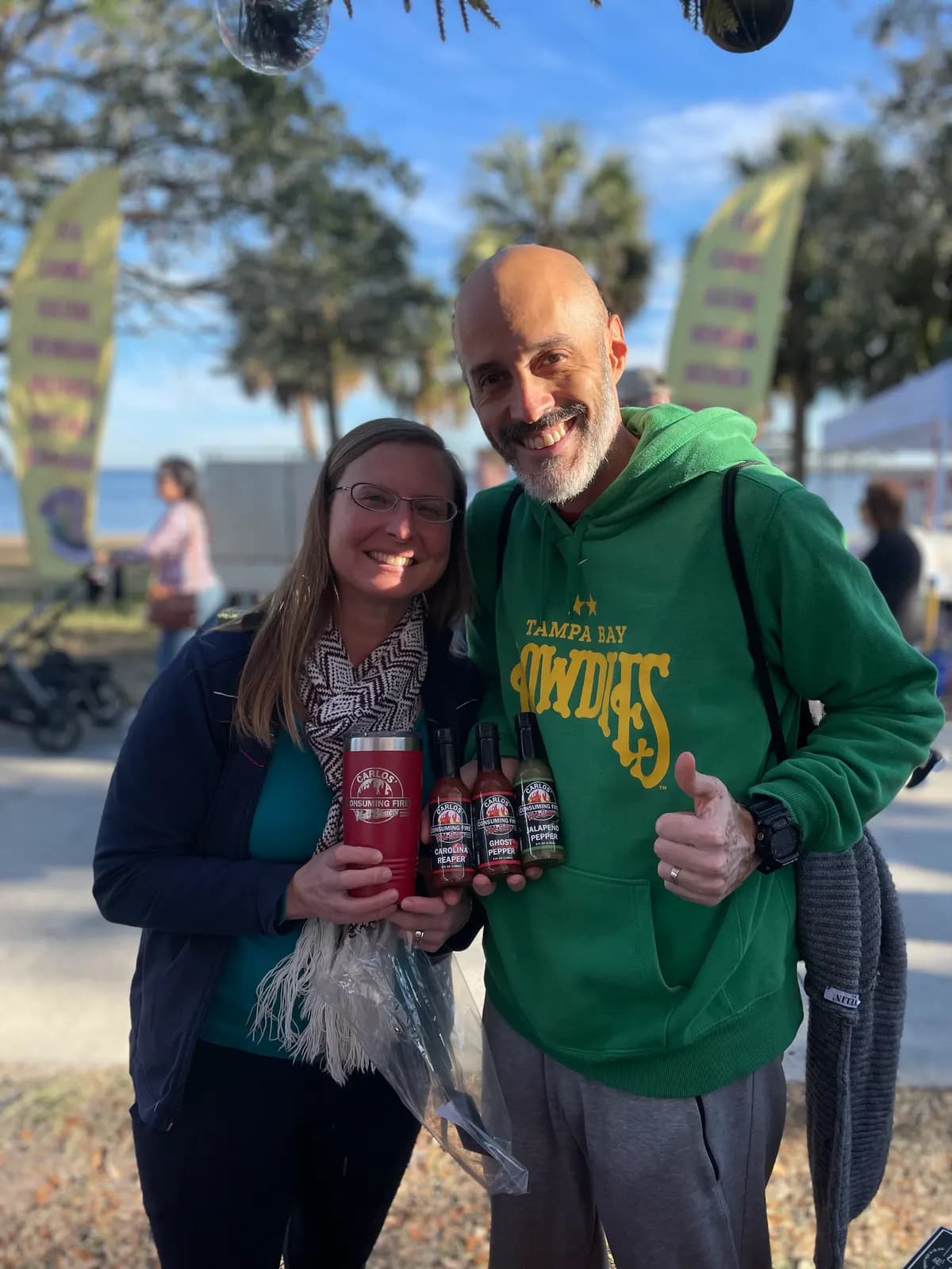 Couple with a branded tumbler and gift pack at a waterfront market
