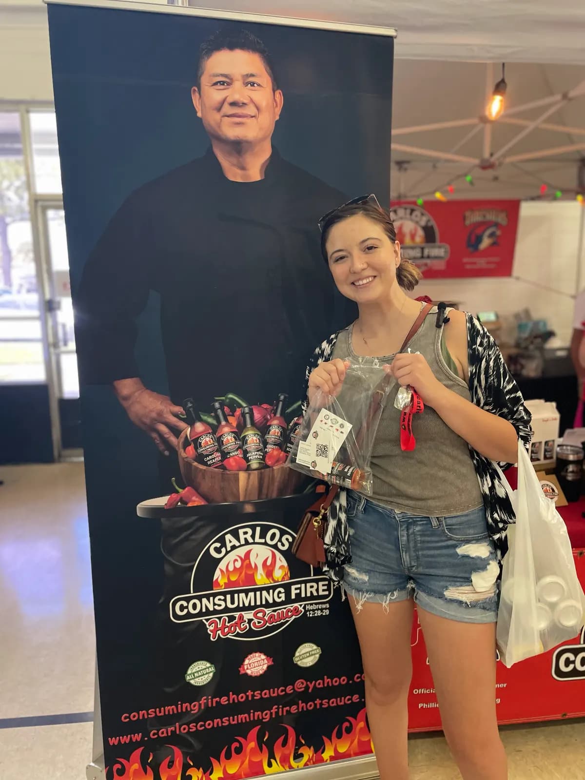 Customer holding a bagged sauce purchase next to the Carlos booth banner