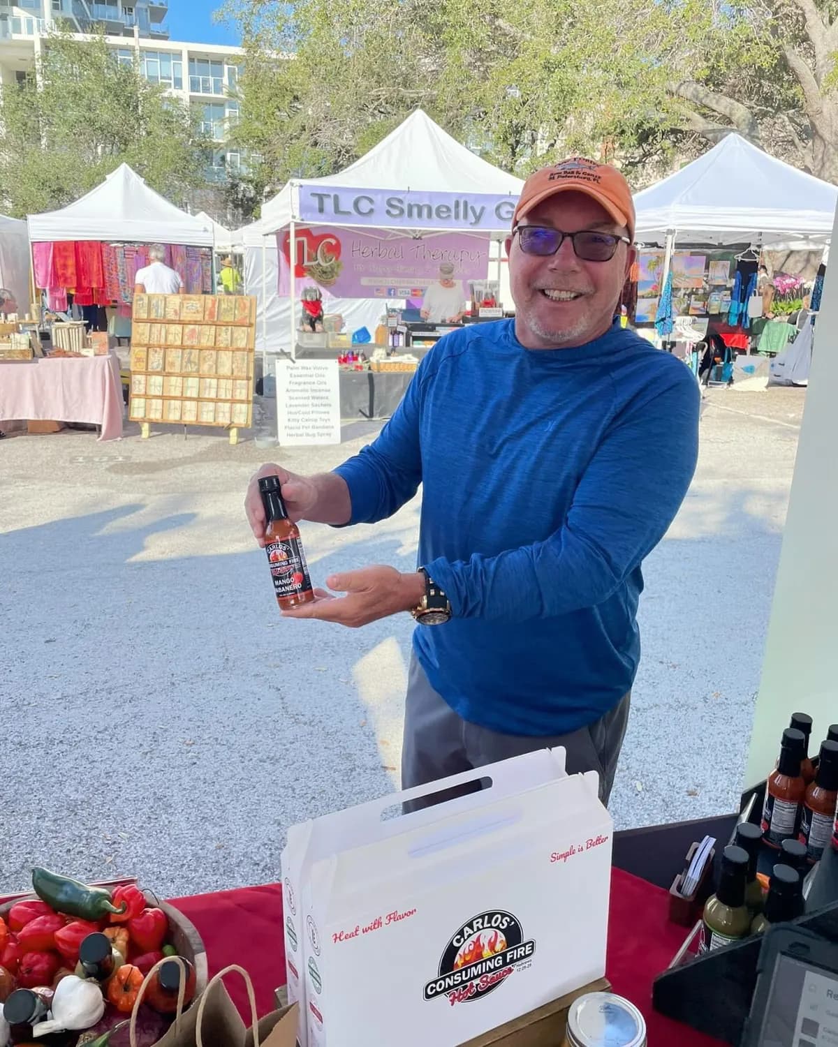 Smiling customer presenting a sauce bottle at an outdoor farmers market