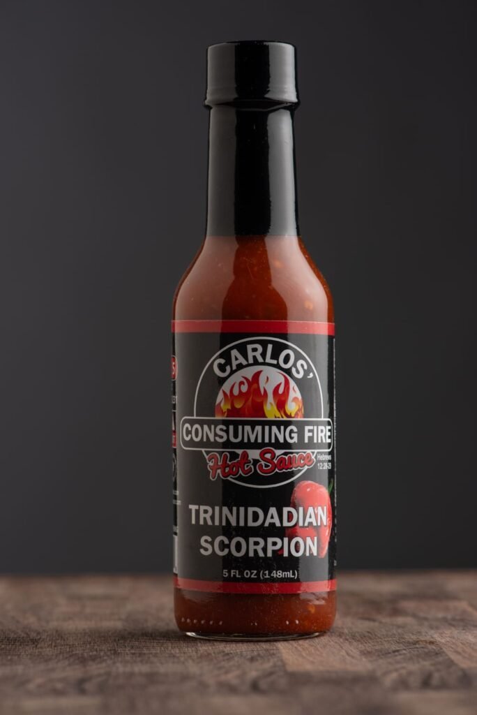 Front view of Carlos' Consuming Fire Hot Sauce Trinidadian Scorpion bottle 5 FL OZ.