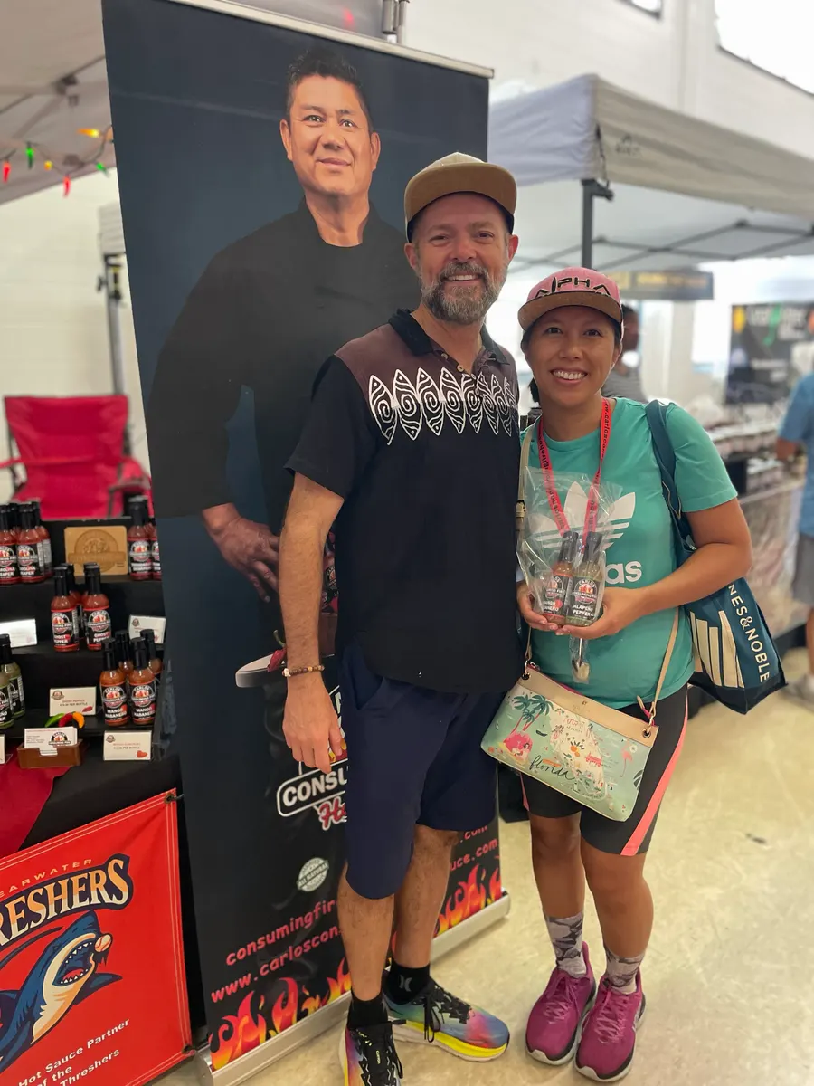 Couple holding a wrapped gift pack of mini sauce bottles at a market booth