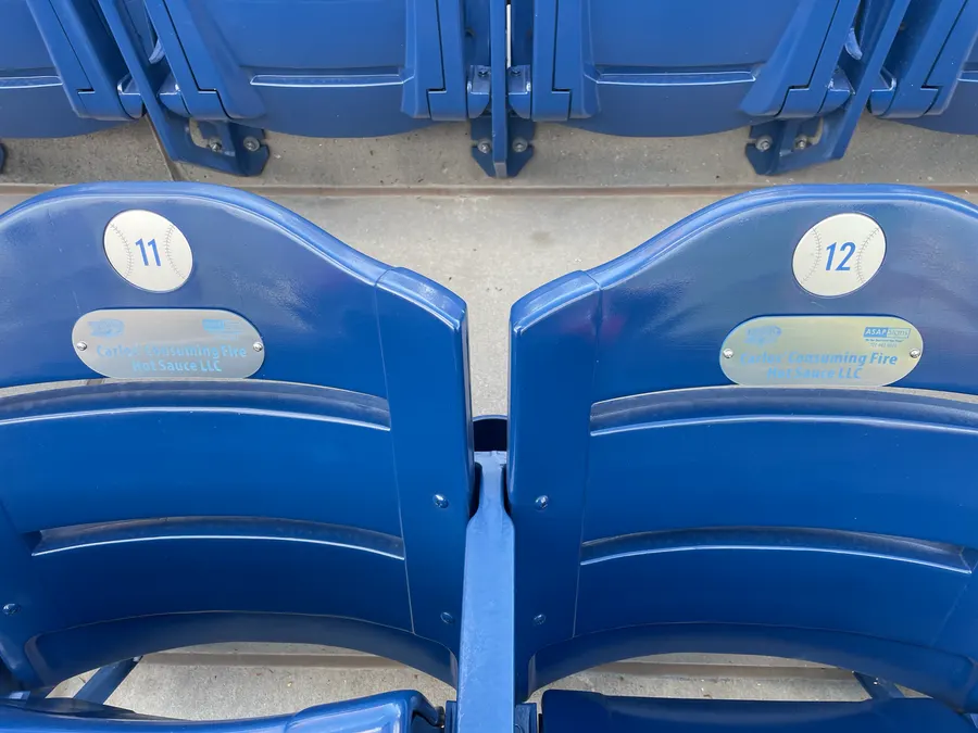 Stadium seats with Carlos' Consuming Fire Hot Sauce sponsor plaques