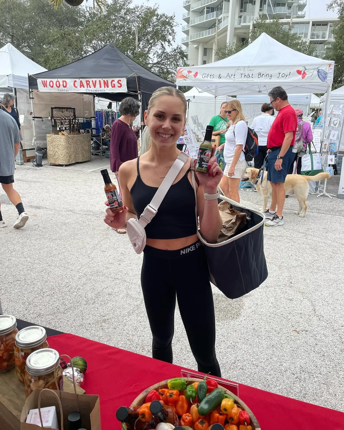 Customer holding two Jalapeño Hot Sauce bottles at a farmers market