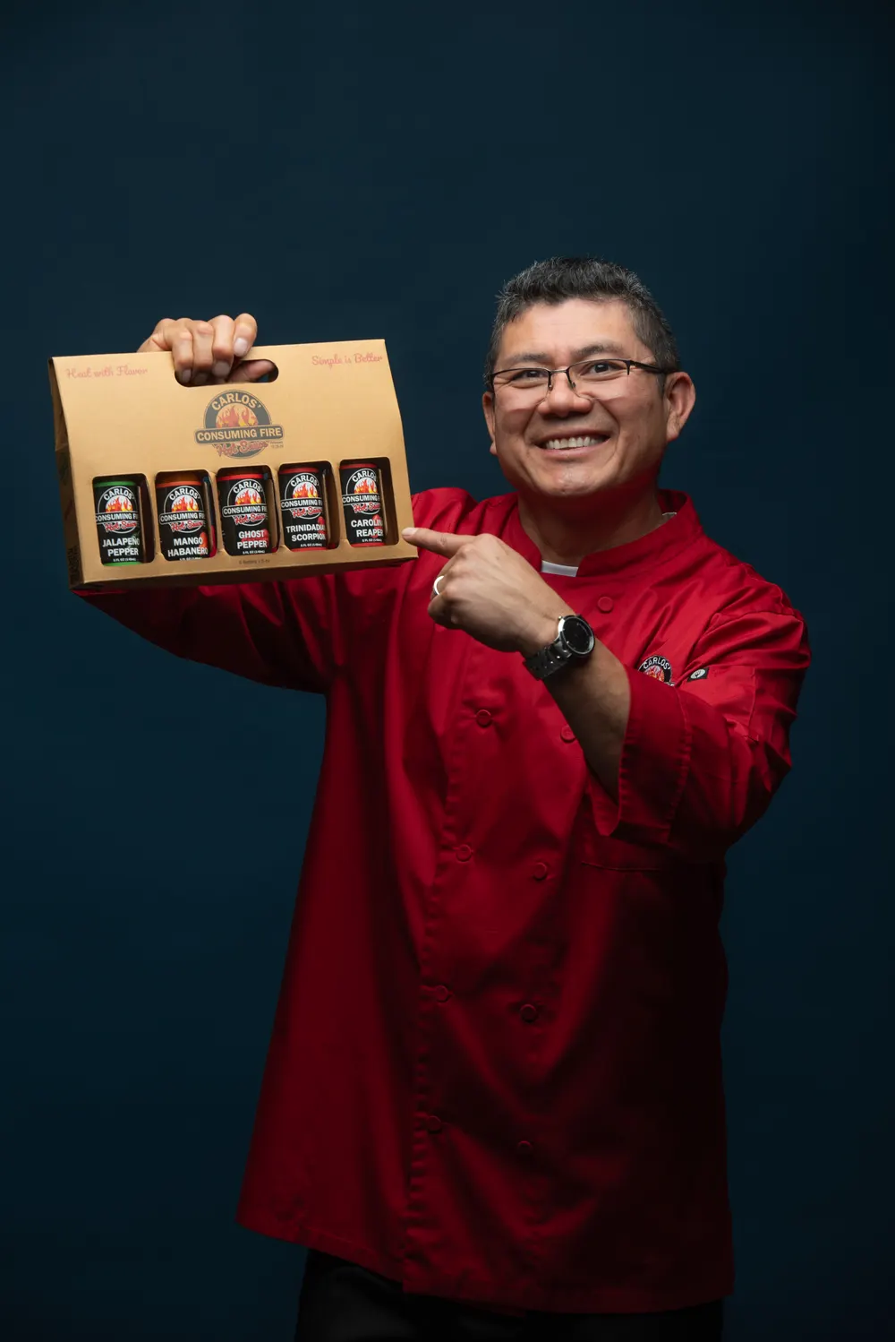 Carlos pointing at the five-bottle gift box he holds at shoulder height