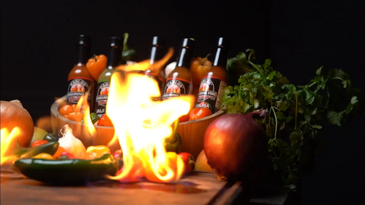 The Carlos' Consuming Fire Hot Sauce lineup behind a live flame